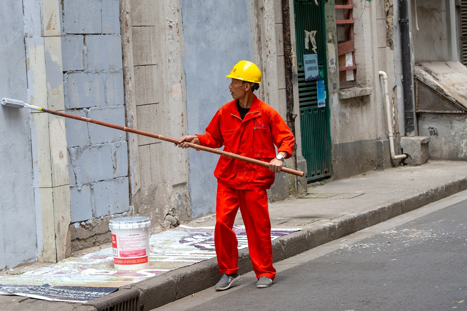 Painter in workwear painting a building wall