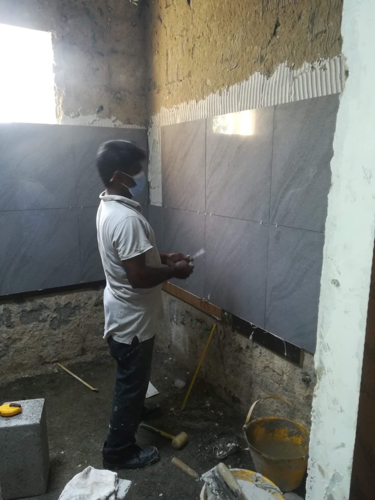 Worker installing tiles on bathroom wall