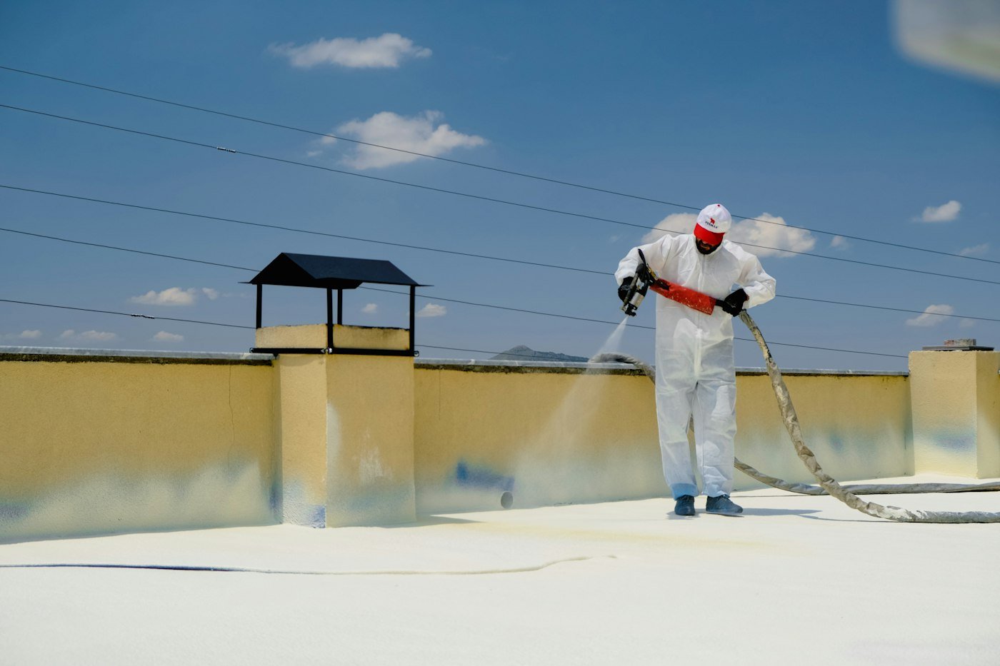 Technician spraying waterproof coating on a building roof